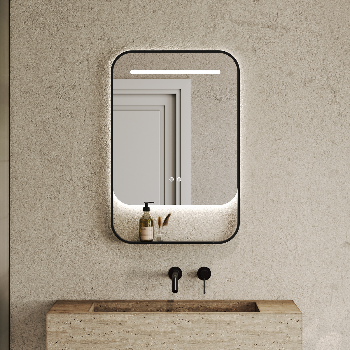 Rounded rectangular black-framed mirror with a glowing top strip above a shelf holding a soap dispenser