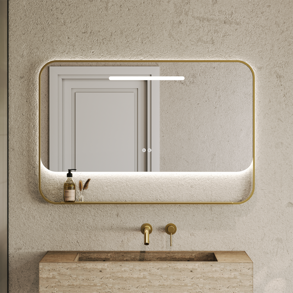 Rectangular brushed gold framed mirror with illuminated top edge and lower shelf holding a soap dispenser